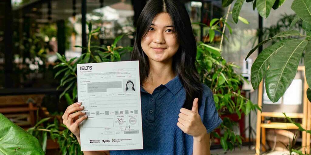 ielc-IELTS-testimonial-student-thumbs-up-holding-IELTS-results